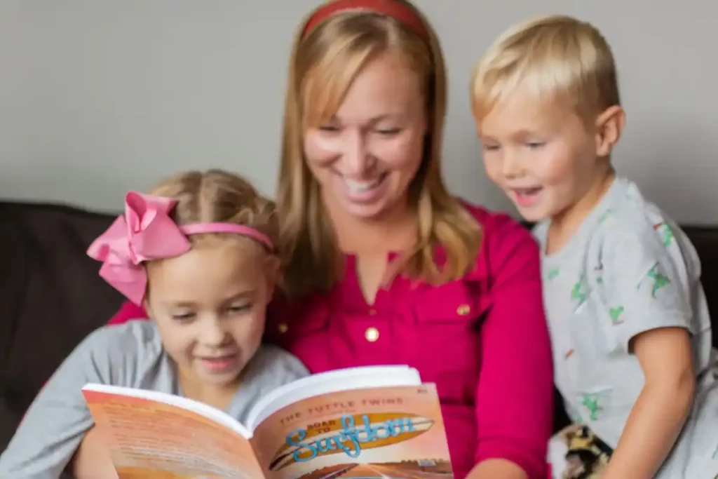 mother reading illustrated children’s book with two kids on couch